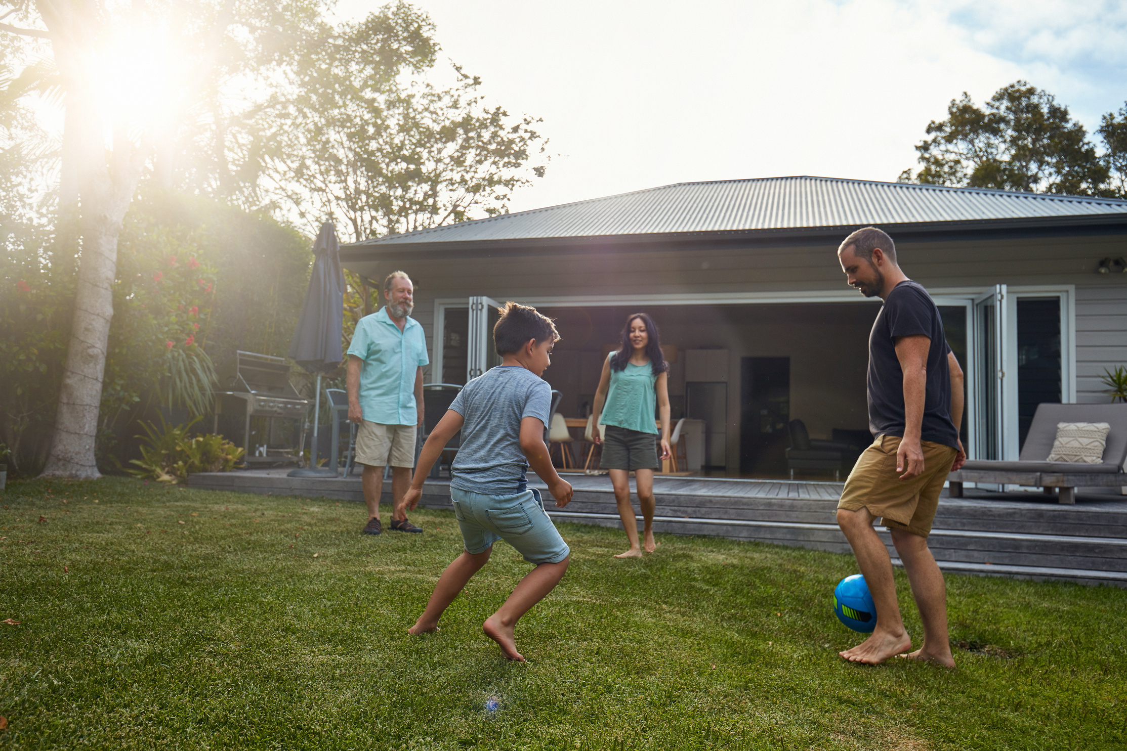 Multi-generation family playing soccer in yard